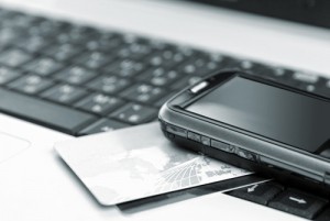 A keyboard with a mobile phone and a credit card ready to use Google Commerce Search (GCS)